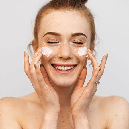 Jeune femme appliquant une crème sur son visage